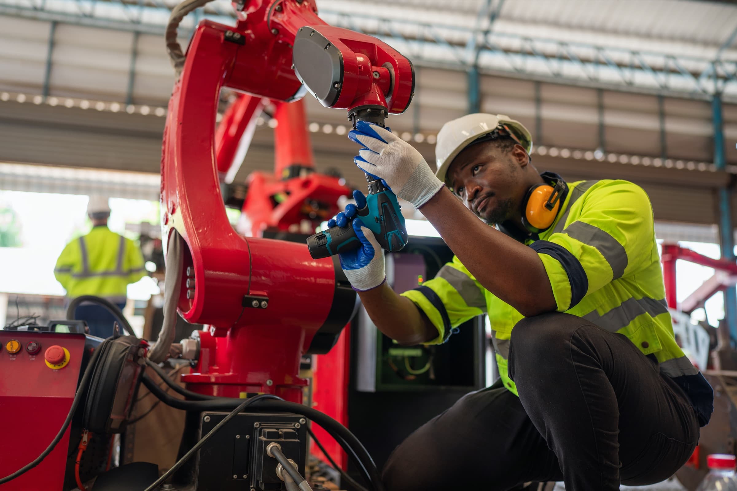 Technician repairing an automated robotic arm in a manufacturing facility