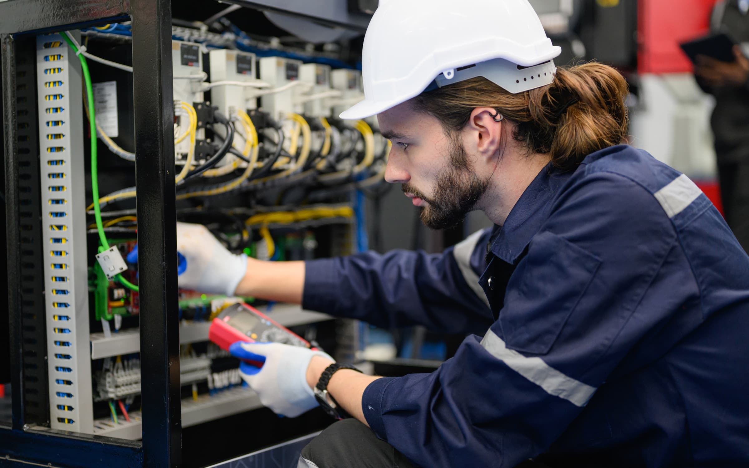 Technician performing PLC maintenance on an electrical control panel